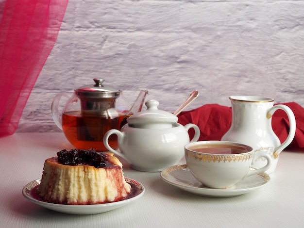 Sheesecake with cherry jam black tea in a teapot a cup with a drink on a light background