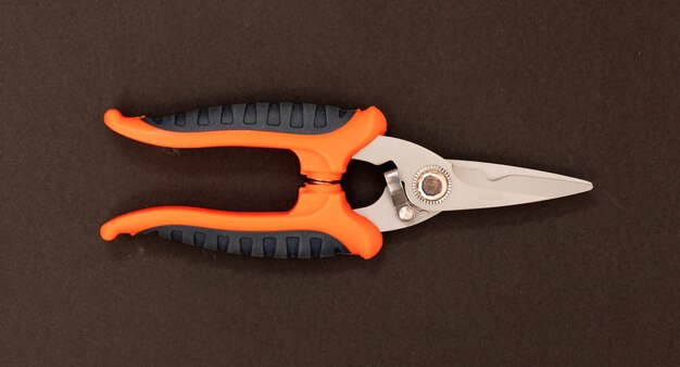 Sheet metal shears scissors steel point orange black color rubber handle on brown background