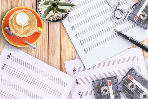 Sheet music cactus fountain pen tape cassette and coffee latte on wooden table