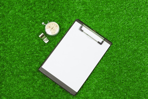 Sheet of paper and sports equipment on grass close-up