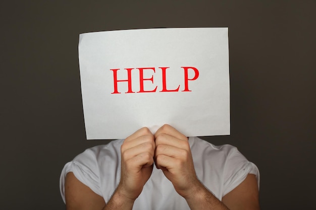 Sheet of paper with Help sign in male hands on dark background