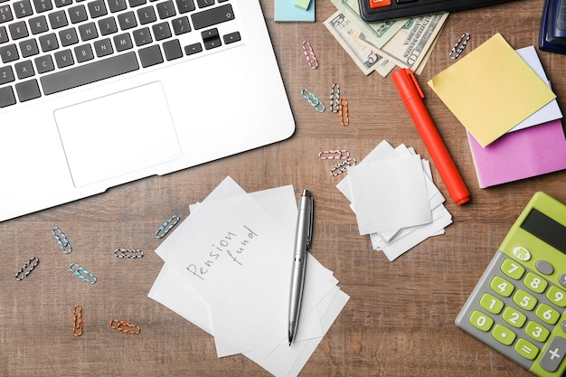 Sheet of paper with text Pension fund and laptop on table