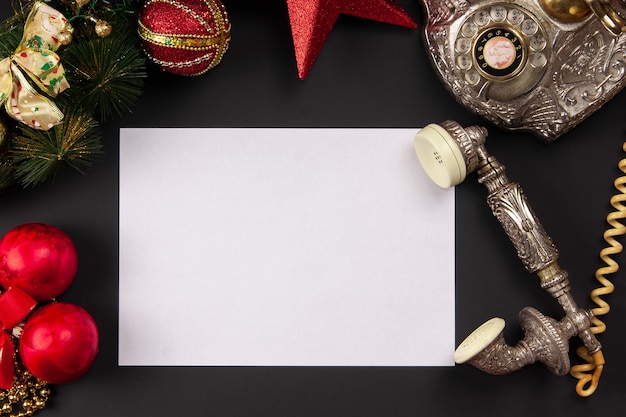 Photo sheet of white paper with vintage telephone on christmas background top view mock up