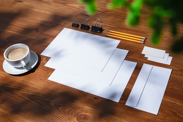 Sheets, coffee and work tools on a wooden table indoors.