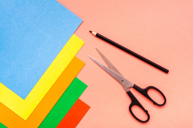 Photo sheets of colored cardboard, scissors and pencil on red