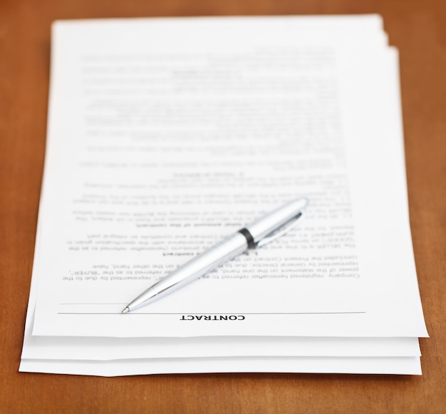 Sheets of contract and silver pen on wooden table