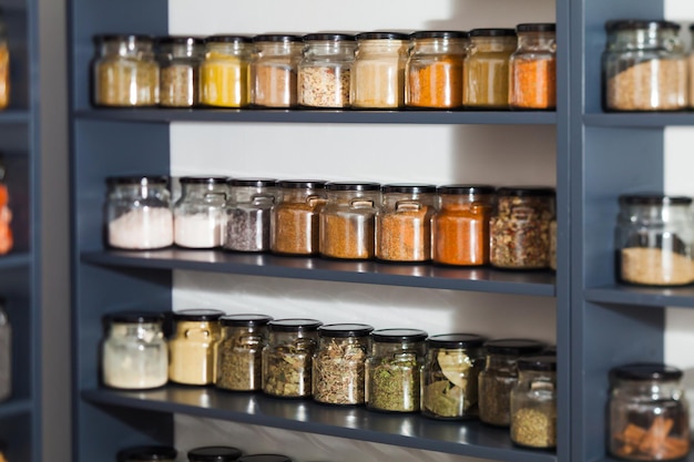 Shelf in a shop with colorful natural spices and powders in glass jars on display. Dry fruits and nuts, cereals in the shop. Grosery market and healthy food and zero waste concept