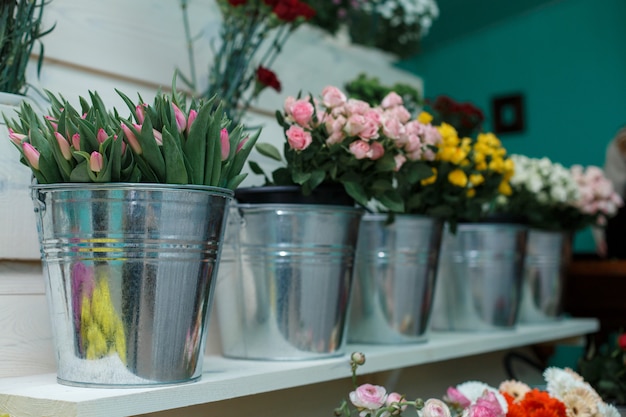 Shelf with roses and tulips in buckets