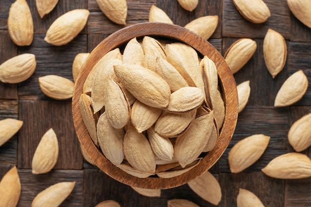 Shelled paper almonds nuts in bowl on wooden table background.