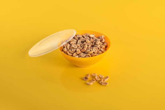 Shelled peanut appetizer in yellow bowl isolated on yellow background