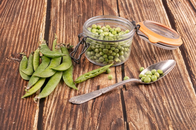 Shelled peas in a glass jar with the pods on the side