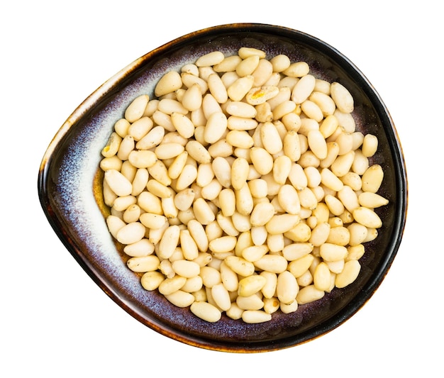 Shelled pine nuts in ceramic bowl isolated