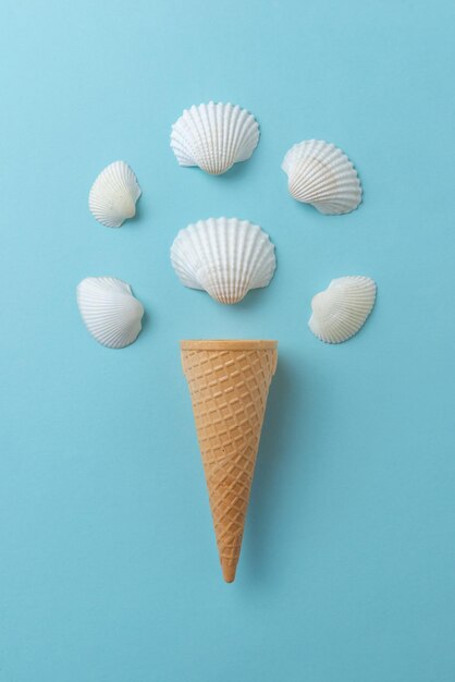 Shellfish ice cream concept on blue surface Ice cream cone with white shells