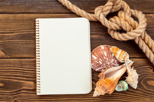 Shells and notepad on wooden table. Top view with copy space