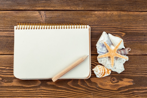 Shells and notepad on wooden table. 