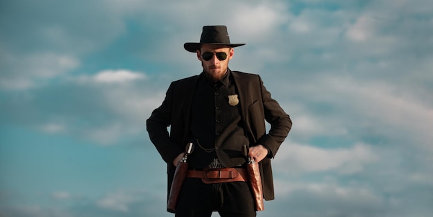 Sceriffo in abito nero e bandiera del cappello da cowboy uomo occidentale selvaggio con revolver a pistola vintage e munizioni maresciallo