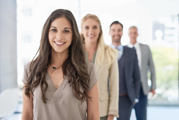 Shes first in line to success Portrait of a young businesswoman standing in a line with her colleagues in an office