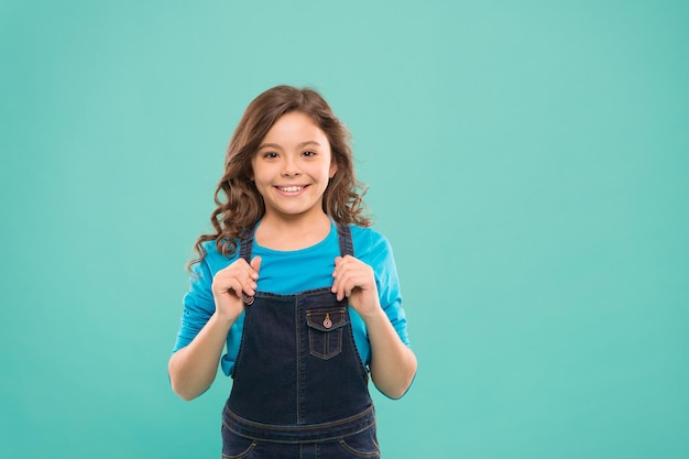 Shes got a pretty smile Little girl with cute smile on blue background Smiling kid with white healthy smile on beautiful face Small child with long brunette hair and happy smile copy space
