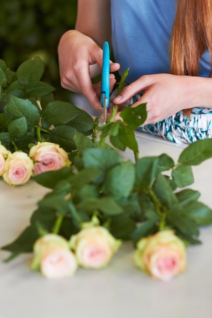 Shes learned the skills necessary for great arranging High angle shot of a florists hands trimming leaves off of rose stems