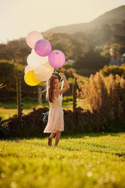 Shes a lucky birthday girl Portrait of a cute little girl holding a big bunch of balloons while walking outside