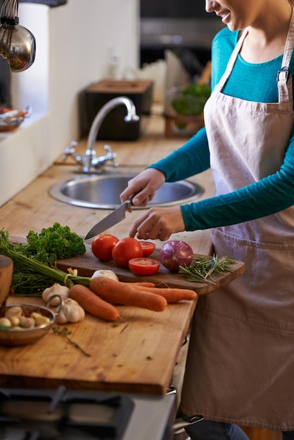 Shes a natural at this Cropped shot of an attractive young woman chopping vegetables in the kitchen