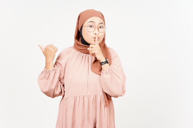 Shh gesture Presenting and Pointing Side Product Using Thumb of Beautiful Asian Woman Wearing Hijab