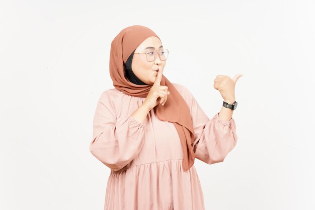 Shh gesture Presenting and Pointing Side Product Using Thumb of Beautiful Asian Woman Wearing Hijab