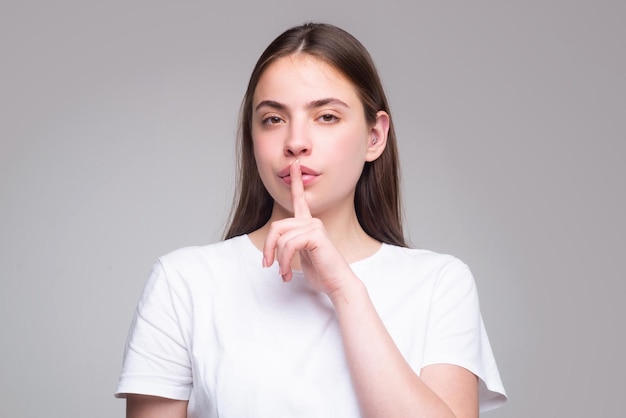 Shh womens secrets woman showing secret sign female with finger in mouth closeup portrait of young w