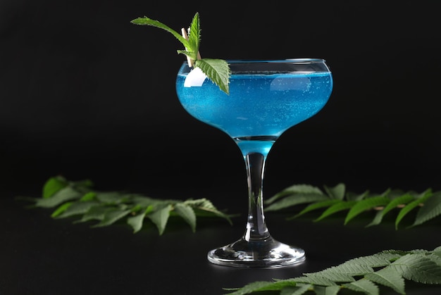 Shimmer edible glitter sparkling blue wine with garnish mint on black background