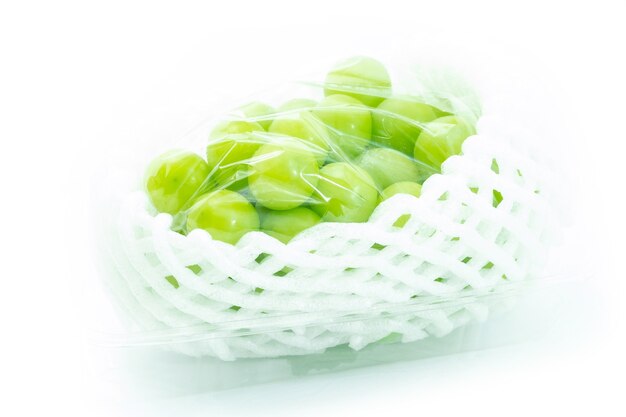 Shine Muscat Grape in packaging and foam cushioning on a white background. Green grapes.