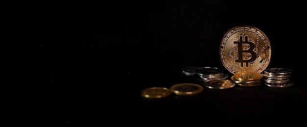 Shining bitcoin standing among coins on black background