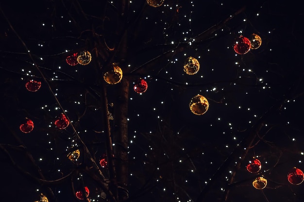 Shining Christmas balls and garlands on the tree at night