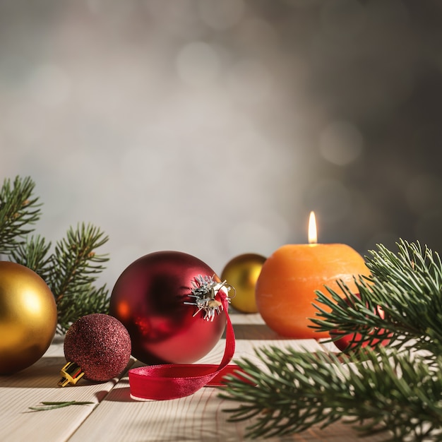 Shiny Christmas balls, burning candle and spruce branch