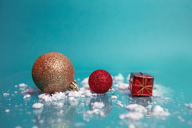 shiny Christmas balls and a small gift on a blue background.