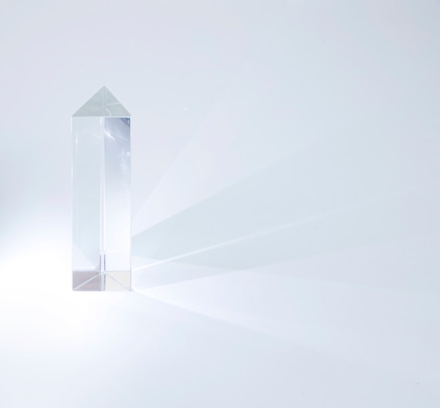 Shiny crystal prism emitting light on white background