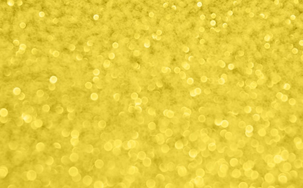 Shiny glitter gold blurred glow background. Shimmering light sparkling texture.