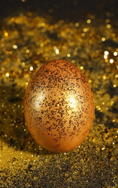 Foto uovo d'oro lucido con glitter sul tavolo scuro