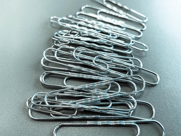 Shiny metal paper clips on a desktop with stationery in a business office Close view