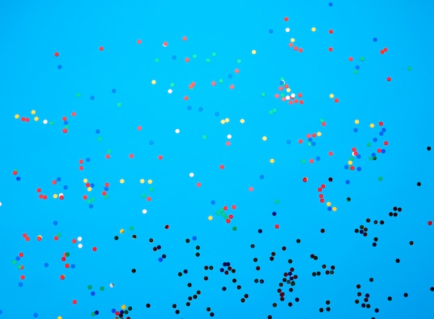 Shiny multicolored round confetti scattered on a blue background