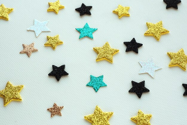 Shiny stars of various sizes and colors lie chaotically on texture paper. abstract background.