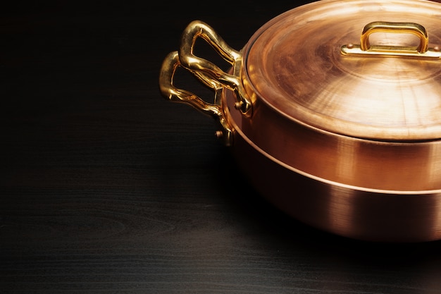 Shiny vintage copper cookware over dark background