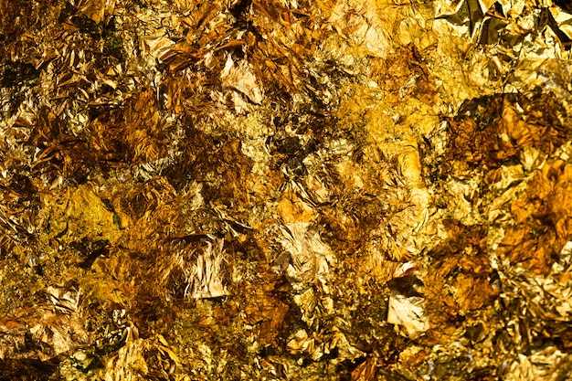 Photo shiny yellow gold leaf or scraps of gold foil background