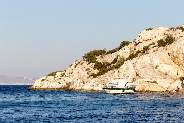 Ship at berth on the background of rocks and the sea on a sunny summer day