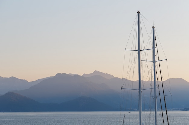 Albero della nave sul cielo e sulle montagne blu di tramonto.