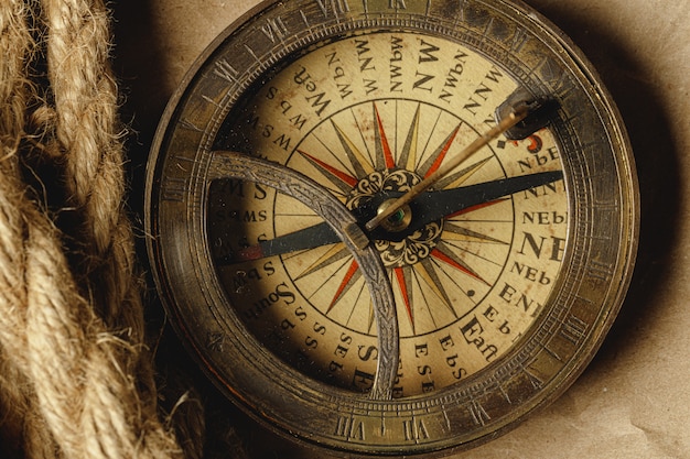 Ship rope and compass on wooden background