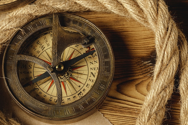 Ship rope and compass on wooden background