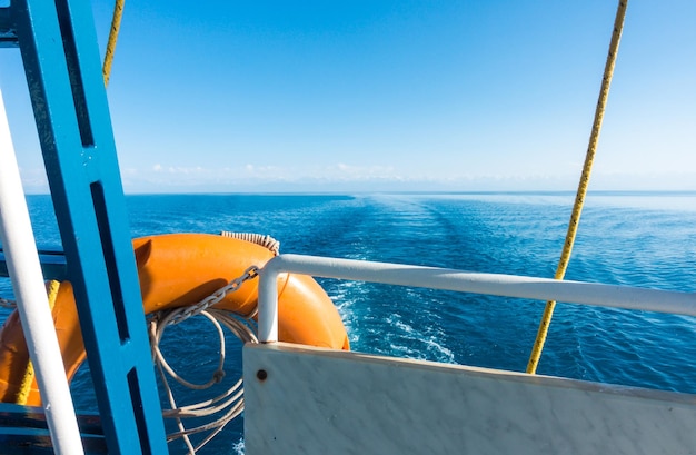 Ship's stern lifeline Footprint on the water from the boat Blue water and mountains on the horizon IssykKul Kyrgyzstan