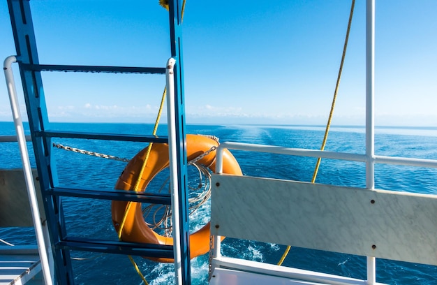 Ship's stern lifeline Footprint on the water from the boat Blue water and mountains on the horizon IssykKul Kyrgyzstan