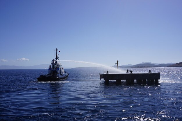 Ship sailing in sea against clear blue sky