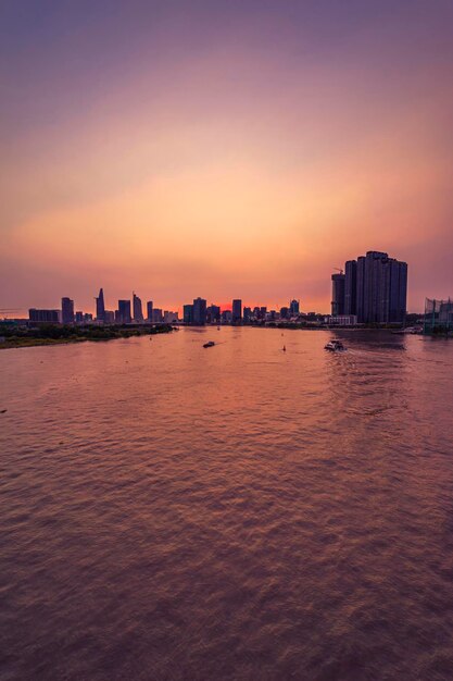 Shipping boat to harbor on saigon river aerial view center ho\
chi minh city vietnam with development buildings transportation\
energy power infrastructure beatiful sunset on the city